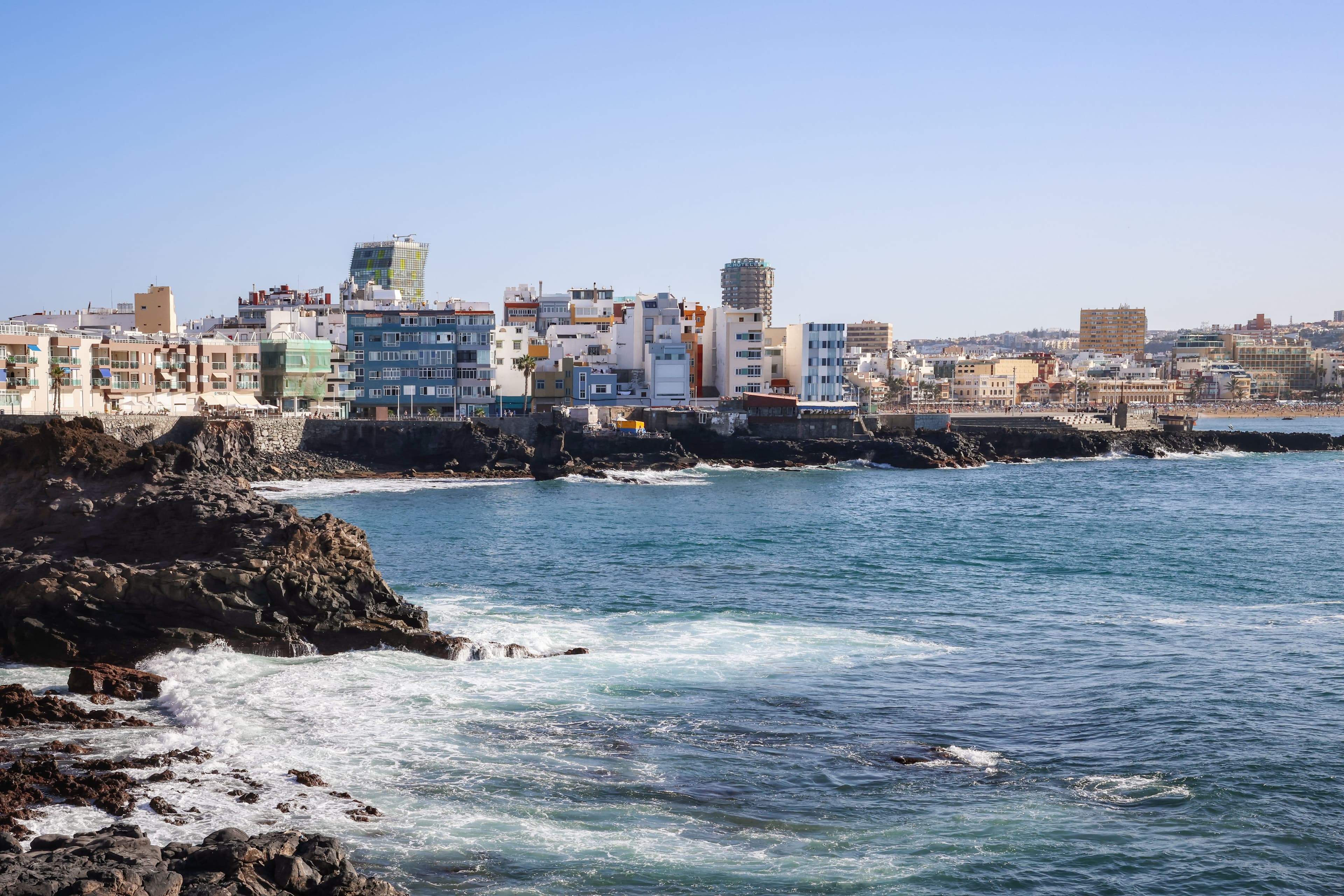 Waves breaking on the volcanic shore below the buildings of Las Palmas