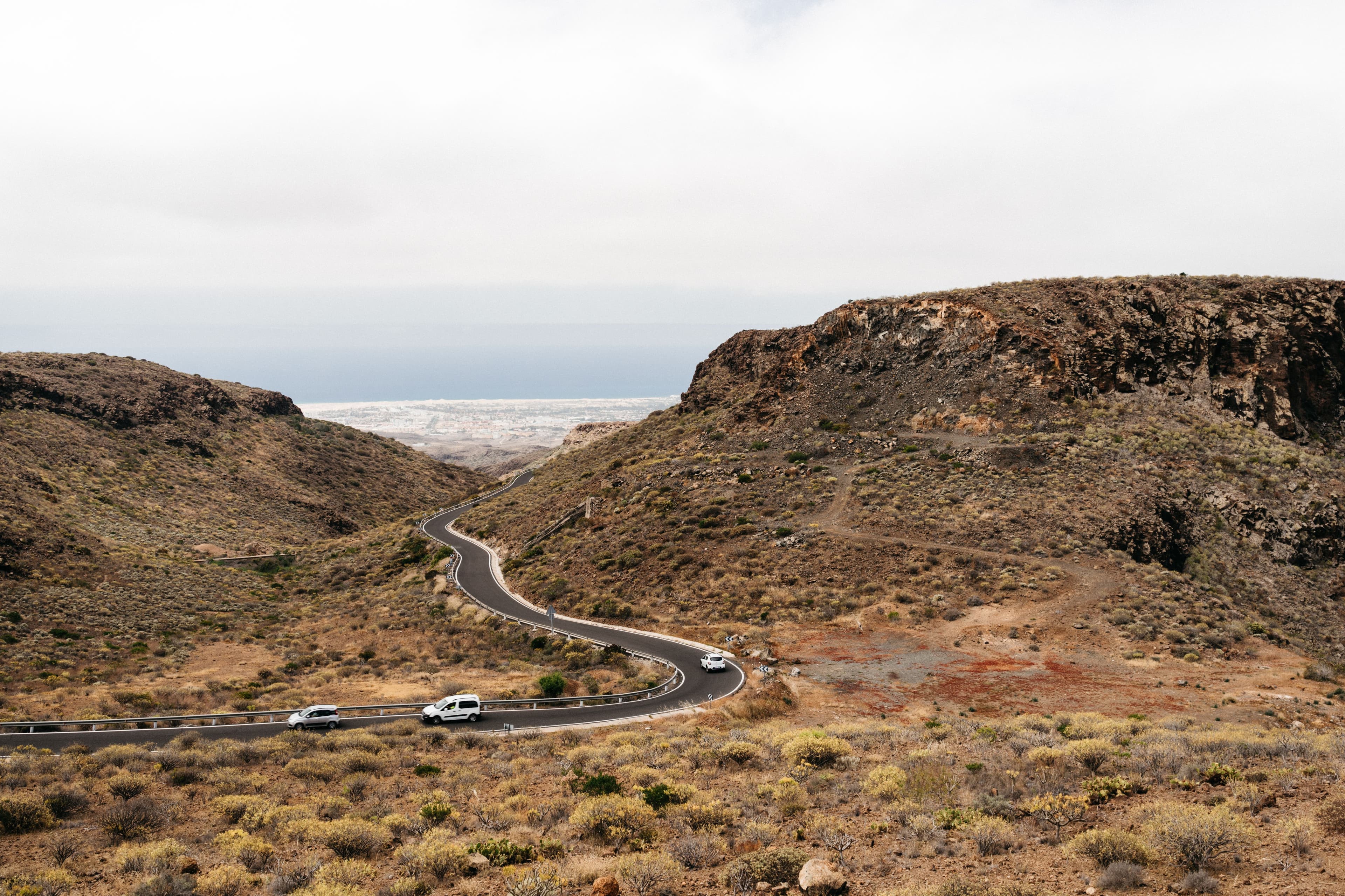 Des voitures descendant une route aride vers la plaine côtière de Gran Canaria